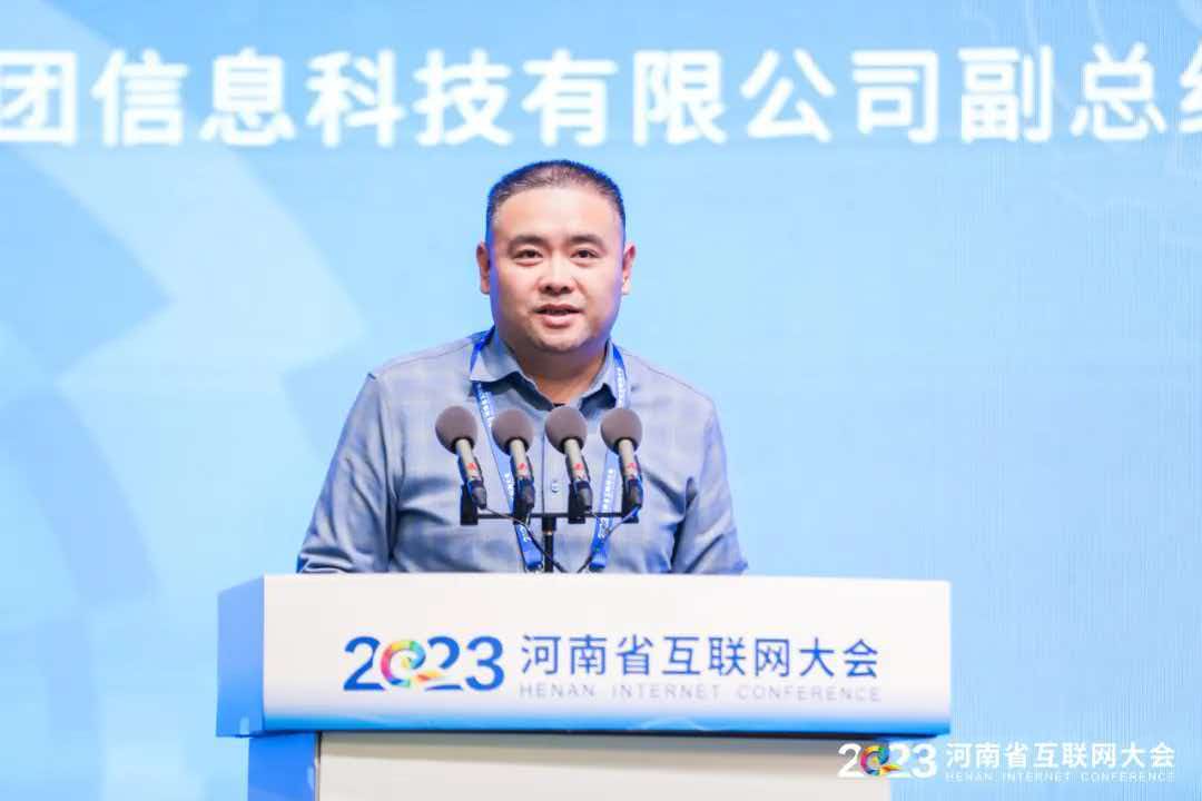 2023河南省互联网大会现场,一名男子站在讲台后发言,面前设有四支麦克风,背景为会议舞台
